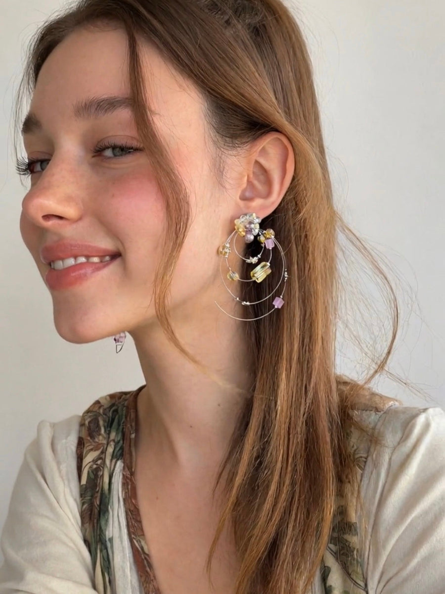 Model wearing dimensional Fullice Iris Halo earrings in soft natural light