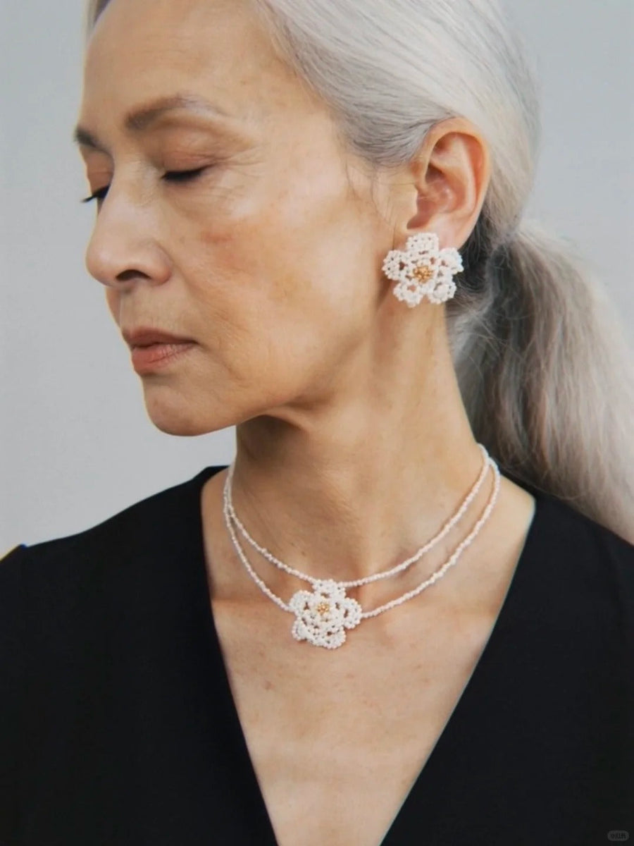 Model in a black top wearing a white Fullice Camellia flower earring and necklace set