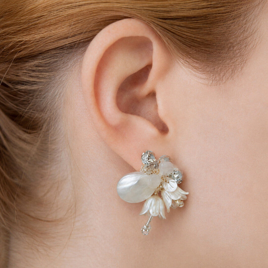 Close-up of a Fullice Magnolia earring with layered white petals and clear bead details